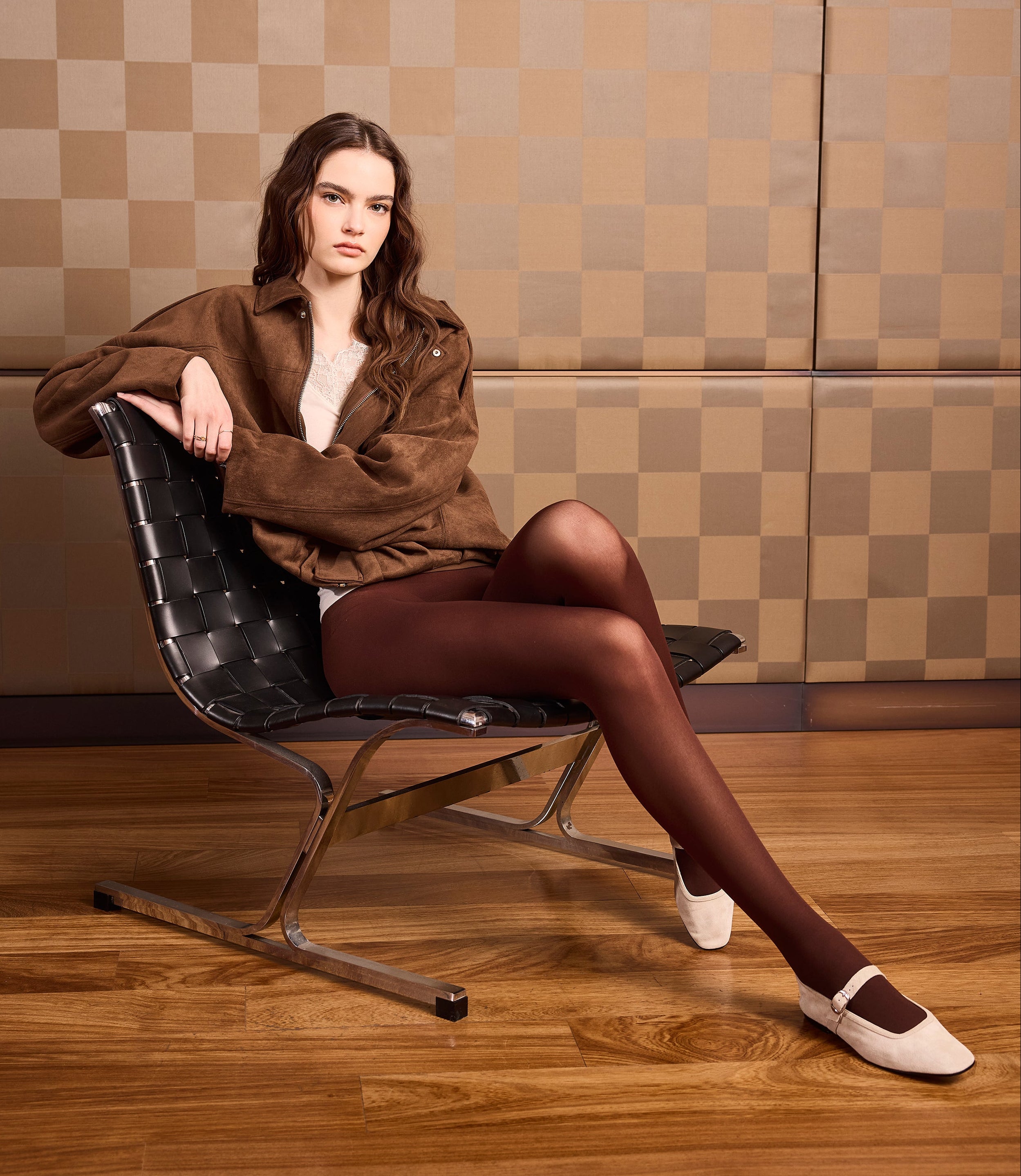 Girl wearing a cream-coloured long-sleeved cashmere jumper. V-neck and lace cuffs. 50 denier opaque tights with a seamless chocolate-coloured bodice.